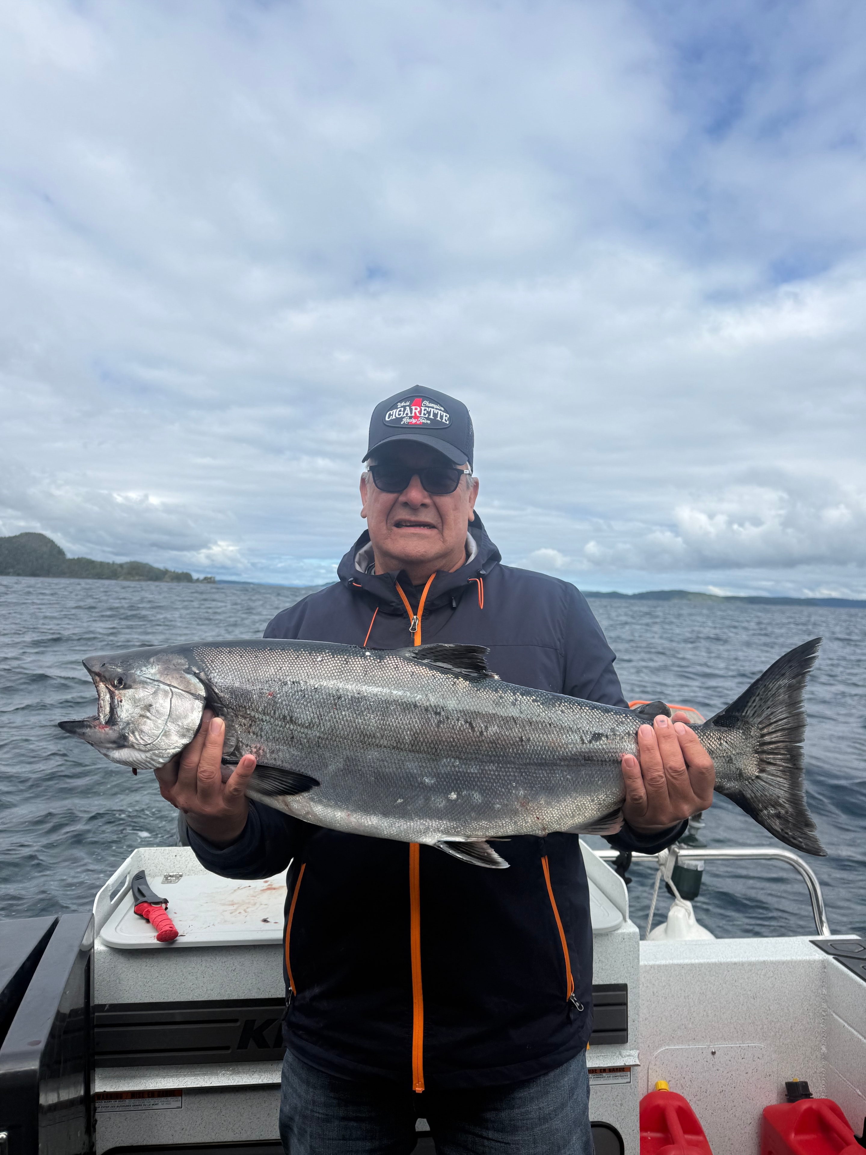 Angler holding salmon on boat with open water behind